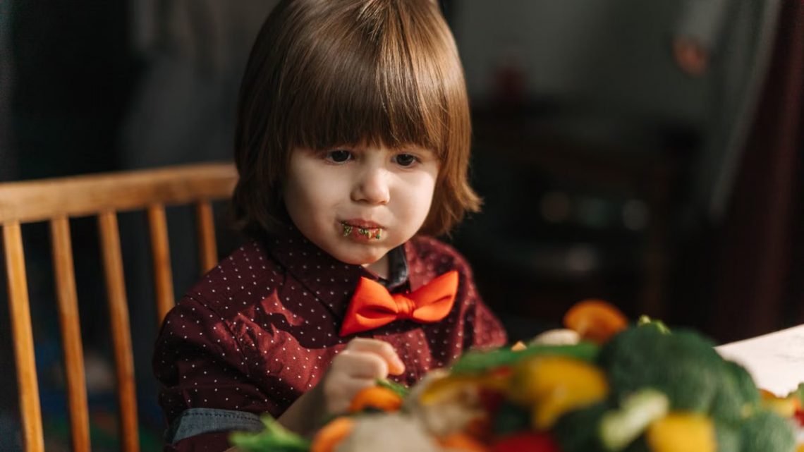 Adorable child enjoying fresh vegetables at the dinner table.